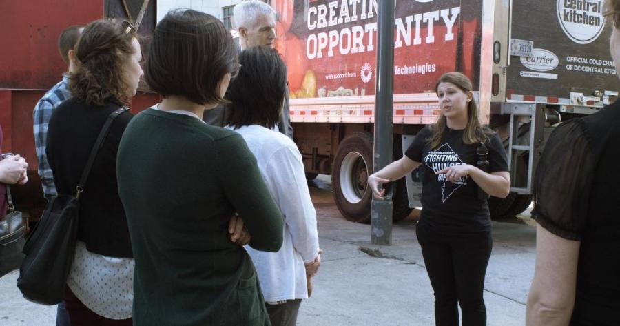 A research team gathers in an alley to learn more about DC Central Kitchen and their food recovery program