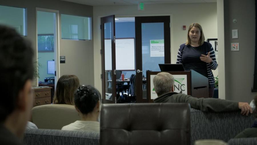 A SESYNC postdoc standing behind a podium presenting to an audience