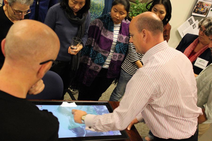 A group of interdisciplinary researchers gathered around a computer screen looking at data