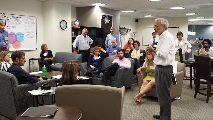 A man stands in front of a group facilitating discussion