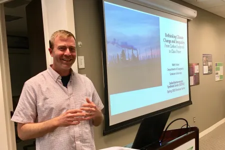 Matt Huber standing behind a podium in front of a presentation projected on a screen