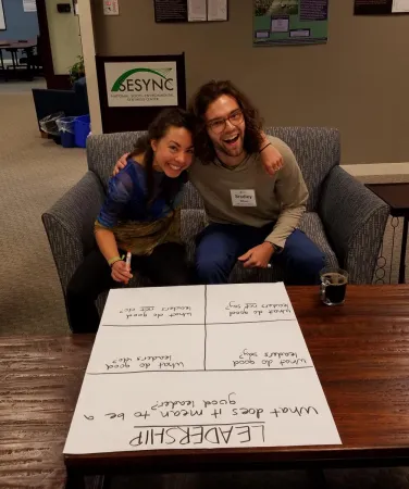 Two grad students seated together working on a poster