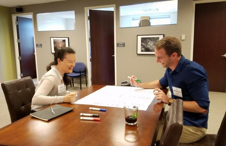 Two graduate students seated at a table working on a poster